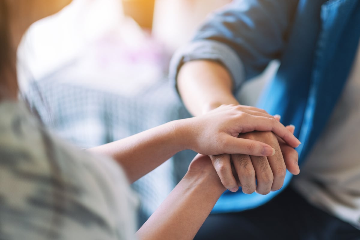 A man and a woman holding each other hands for comfort and s